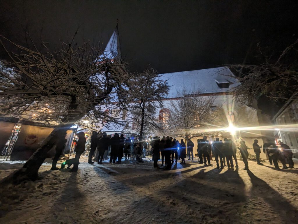 Weihnachtsmarkt bei einer Kirche am Abend.